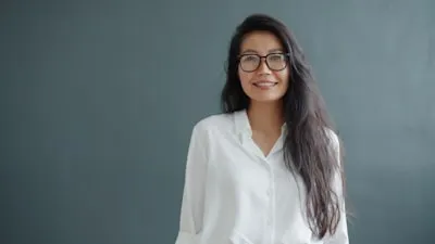 Retrato de Alexandra Bennett de óculos e camisa branca, sobre fundo cinza