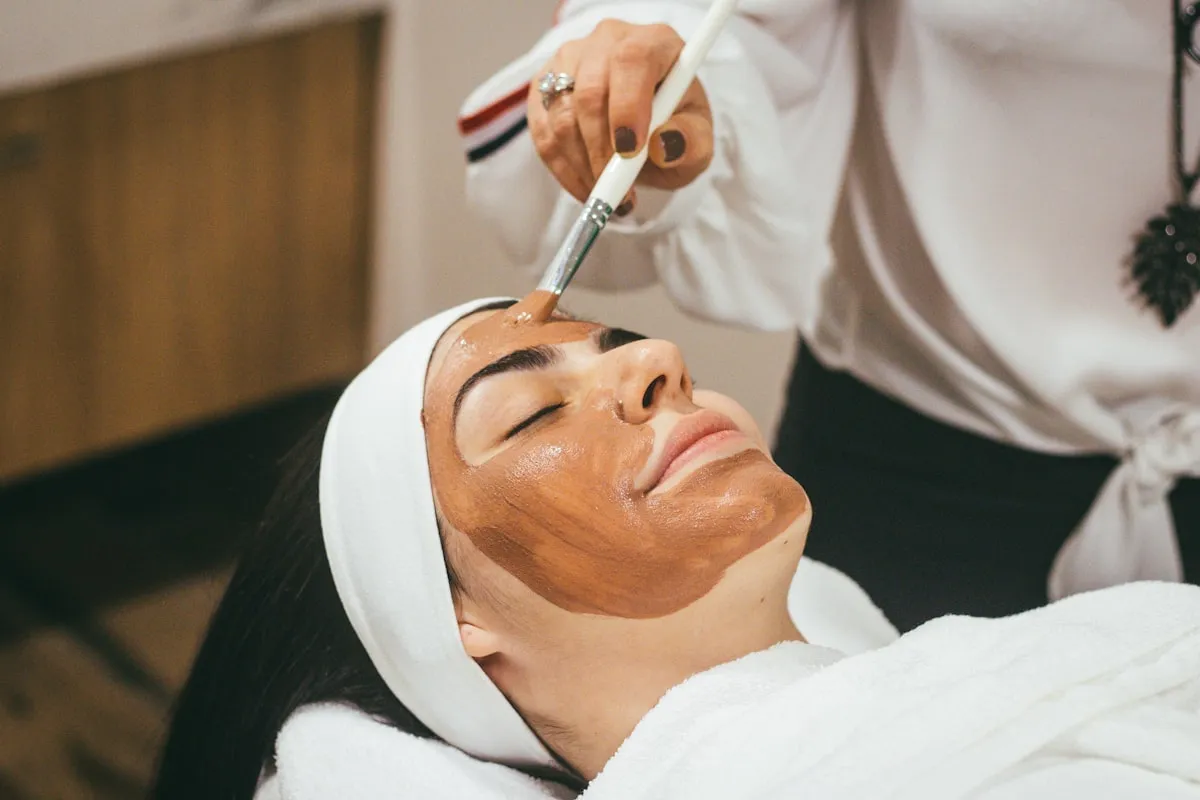 Aplicação de máscara facial com pincel em uma cliente deitada