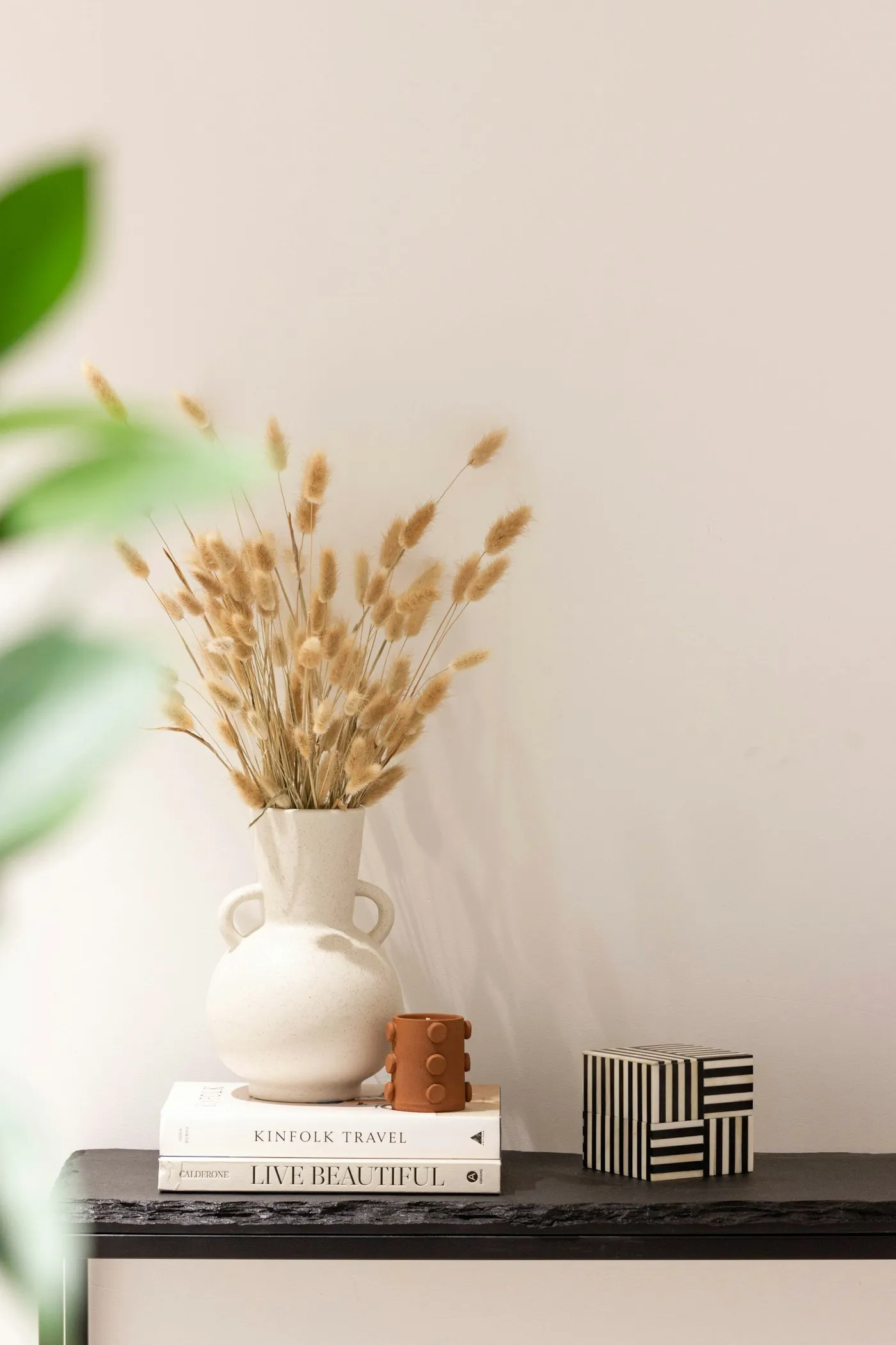 Vaso de cerâmica com capim-dos-pampas seco sobre uma mesa lateral